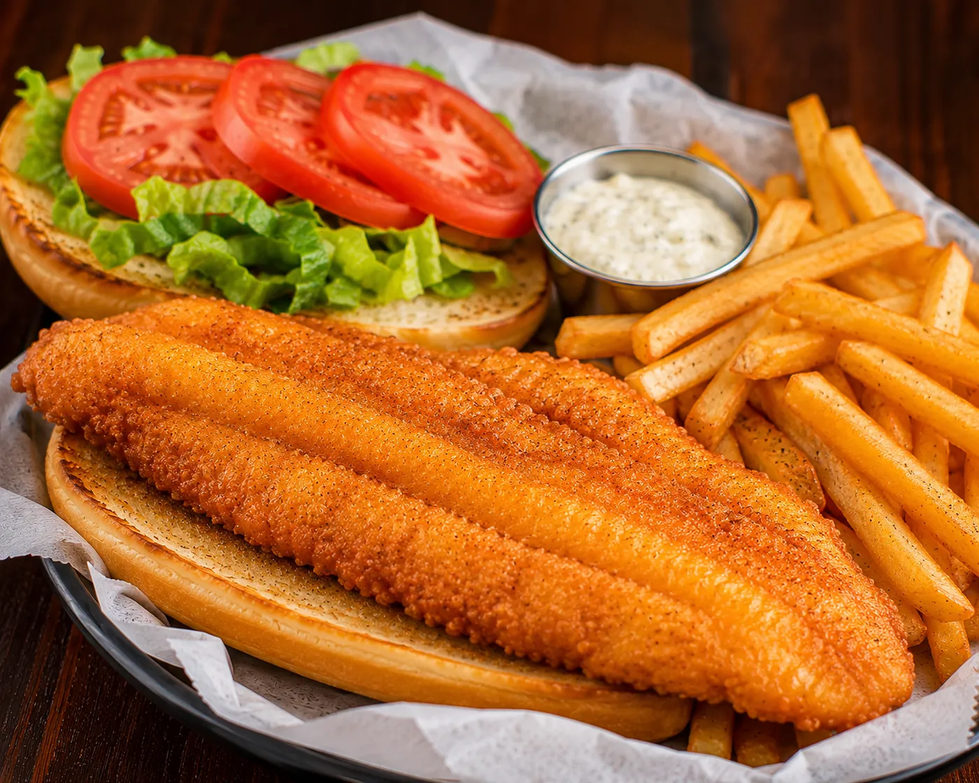Golden fried fish sandwich with lettuce, tomato, tartar sauce and fries at Buzz City in Charlotte