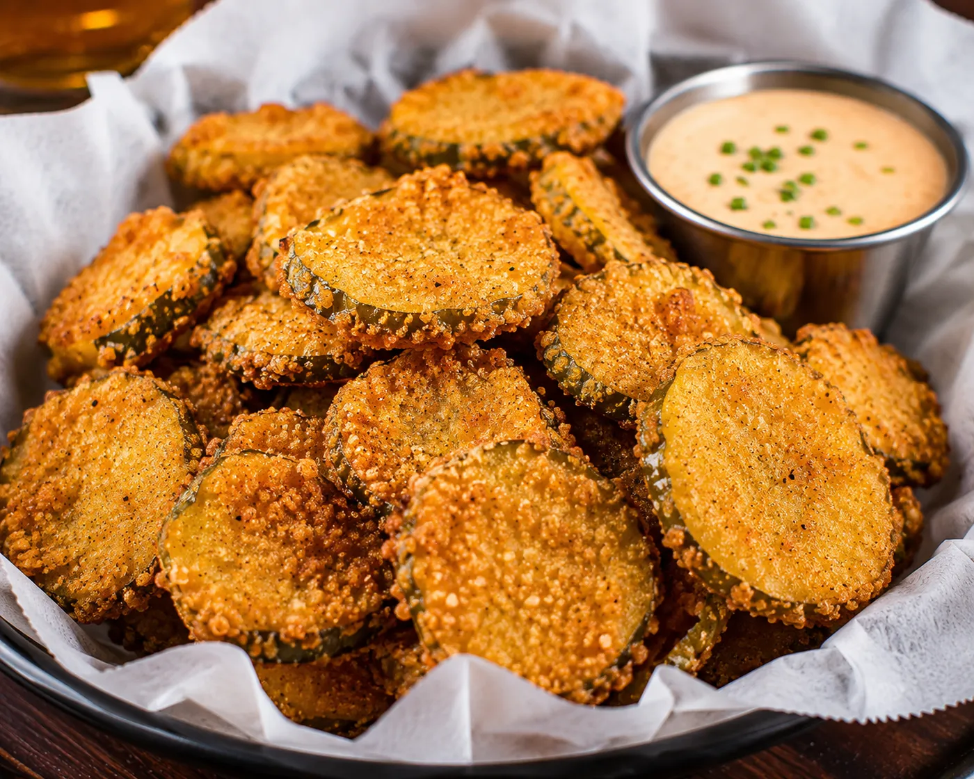 Basket of crispy fried pickles with dipping sauce at Buzz City