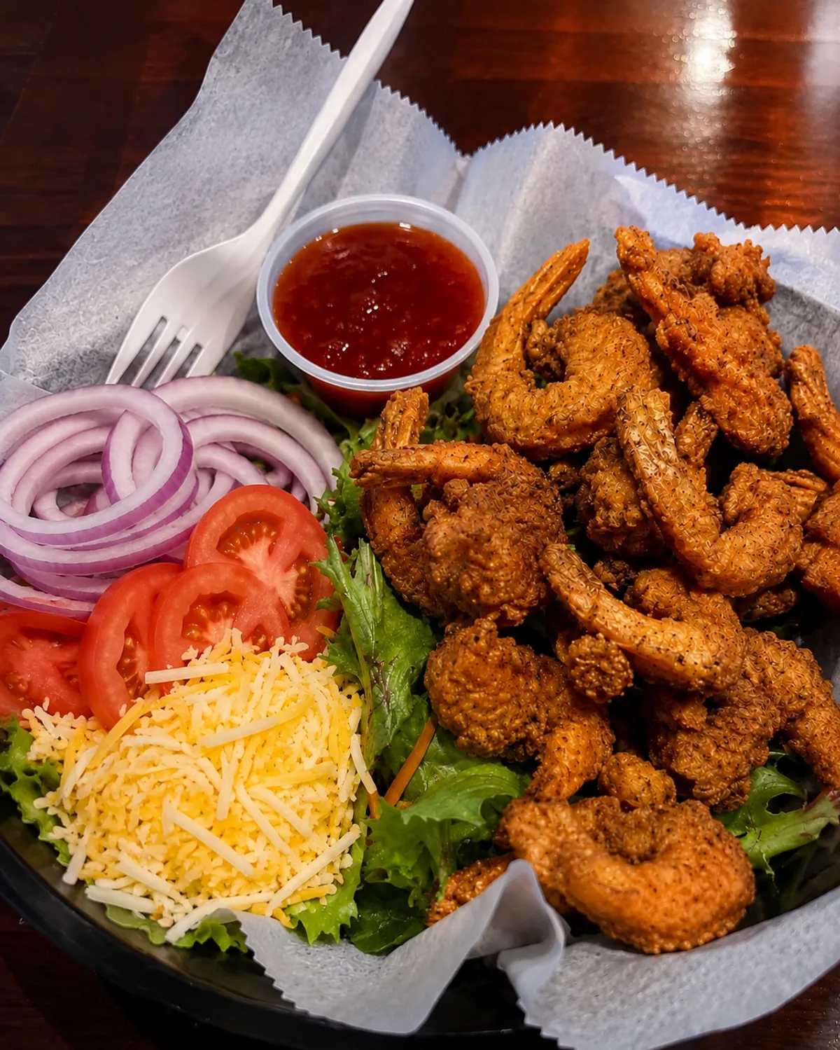 Fried shrimp salad with lettuce, tomato and cheese at Buzz City